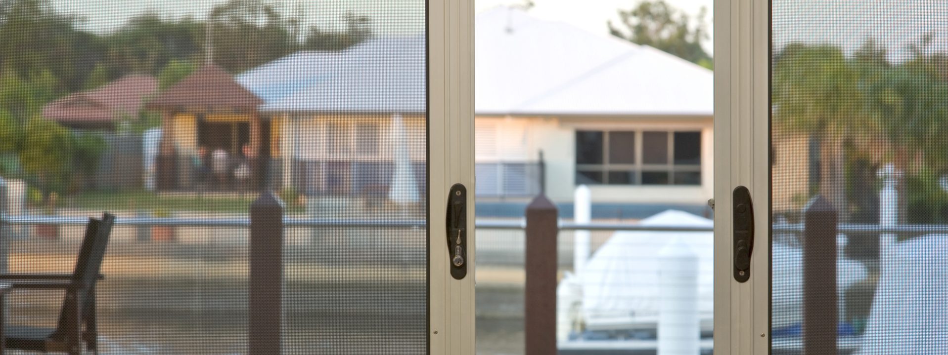 A close-up of an aluminium sliding security screen door located within an Balcatta backyard.